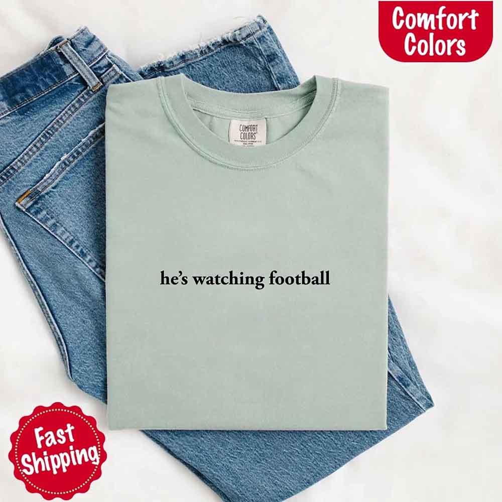 He’s Watching Football Tee - Comfort Colors Funny Shirt for Her